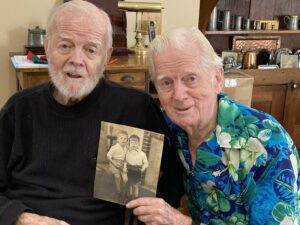 Jack and Jim side by side holding a photo of themselves as children