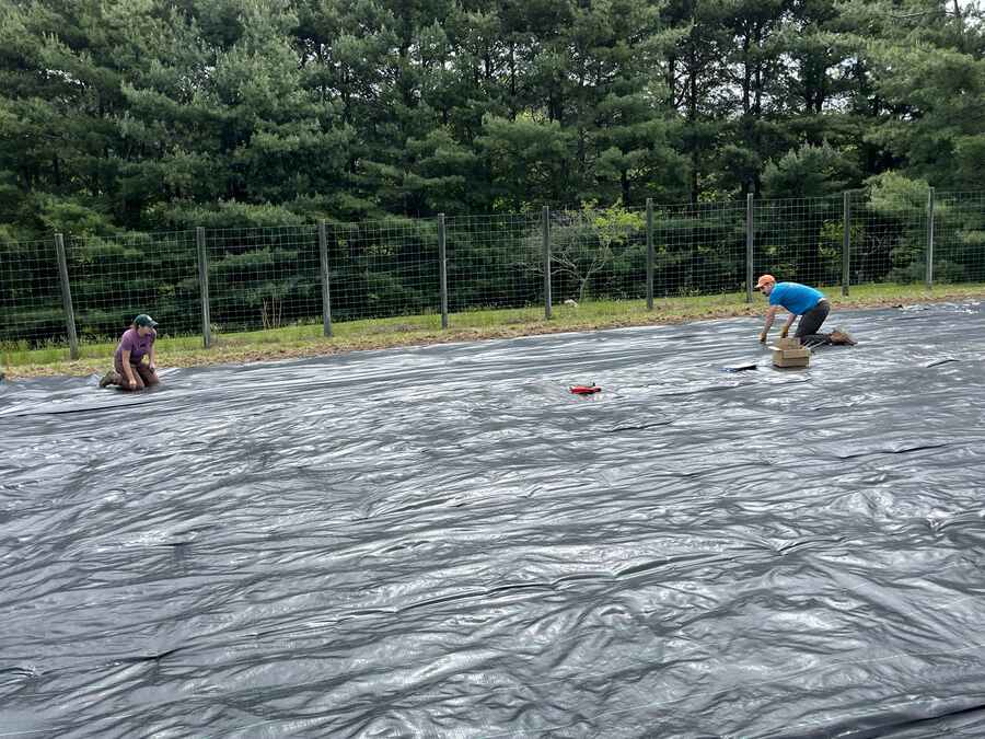 Installing landscape fabric for weed control in the Germplasm Conservation Orchard by Jamie Van Clief and volunteers.