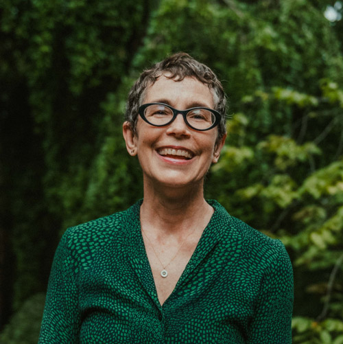 Matguerite Holloway headshot. She wears a patterned green blouse and glasses.